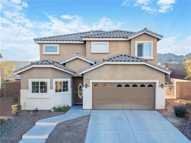 view of front of house featuring concrete driveway, fence, a tile roof, and stucco siding