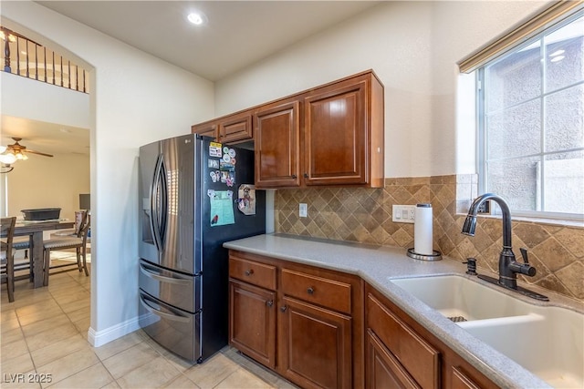 kitchen with stainless steel refrigerator with ice dispenser, light tile patterned floors, light countertops, backsplash, and a sink