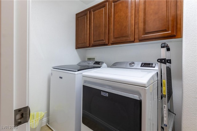 clothes washing area featuring washer and dryer and cabinet space