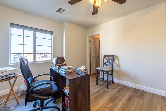 office area featuring a ceiling fan, visible vents, baseboards, and wood finished floors