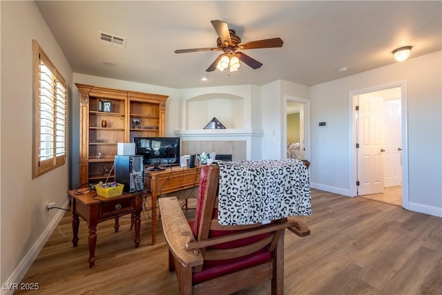 living area featuring baseboards, visible vents, wood finished floors, and a tile fireplace