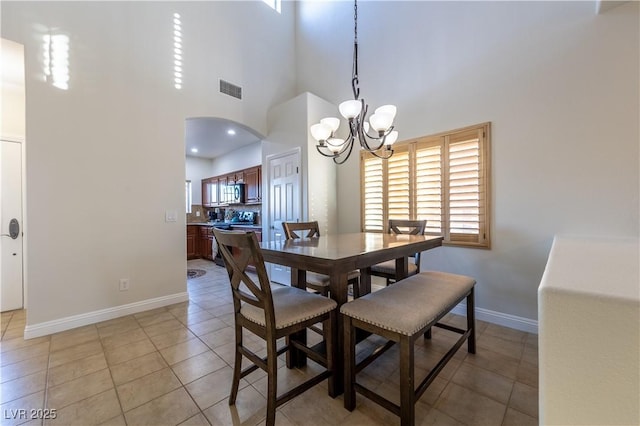 dining space featuring light tile patterned floors, baseboards, visible vents, and arched walkways