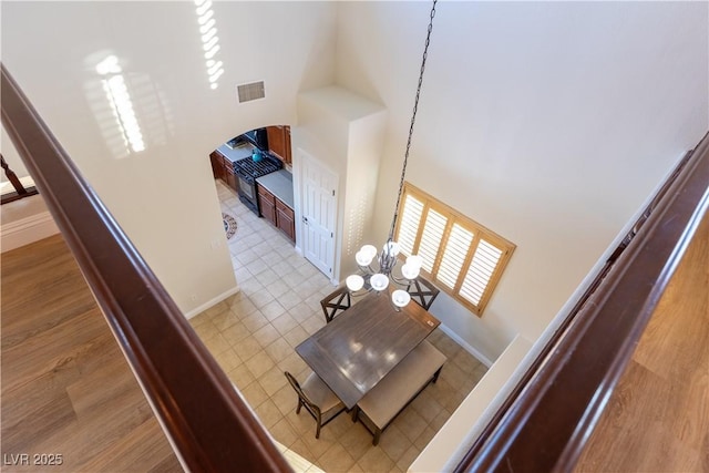 interior space featuring arched walkways, a high ceiling, visible vents, and baseboards