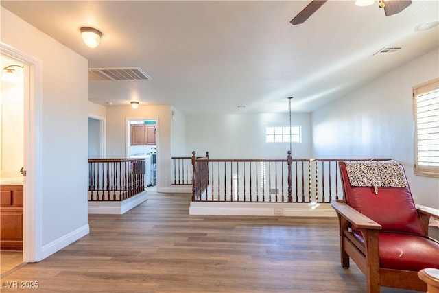 sitting room with an upstairs landing, wood finished floors, and visible vents