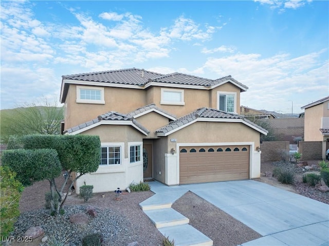 view of front of house with driveway, a tiled roof, a garage, and stucco siding