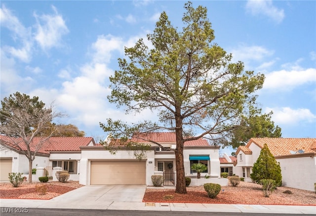 mediterranean / spanish house featuring concrete driveway, a tile roof, an attached garage, and stucco siding