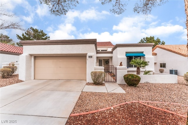 mediterranean / spanish-style home featuring a garage, driveway, central AC unit, a gate, and stucco siding