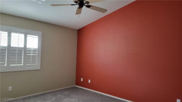 carpeted spare room featuring baseboards and a ceiling fan