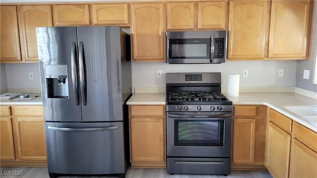 kitchen with light brown cabinets, stainless steel appliances, and light countertops