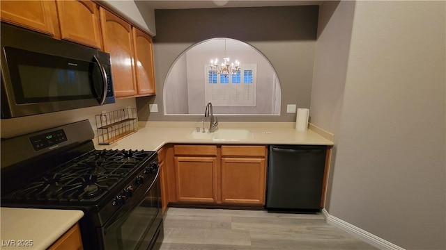 kitchen featuring a sink, brown cabinets, black appliances, and light wood finished floors