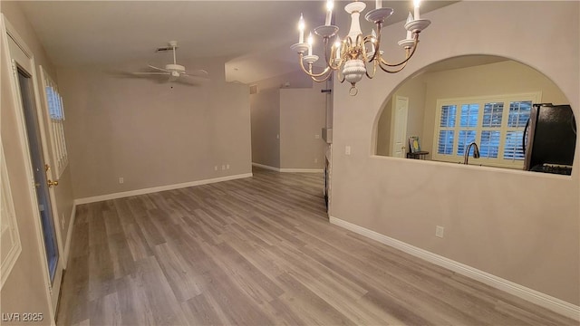 spare room featuring visible vents, baseboards, wood finished floors, and ceiling fan with notable chandelier