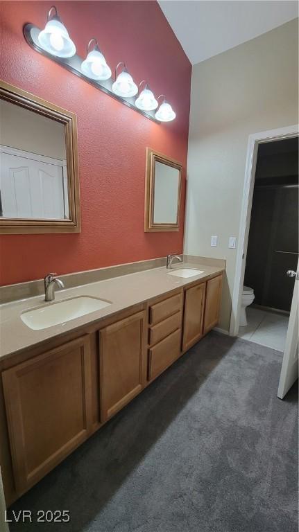 full bath with tile patterned flooring, double vanity, toilet, and a sink