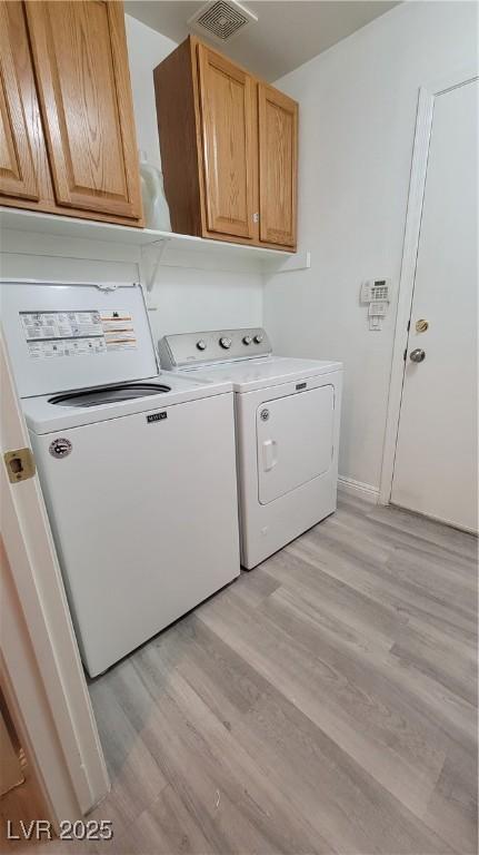 clothes washing area featuring visible vents, baseboards, light wood-style flooring, cabinet space, and separate washer and dryer