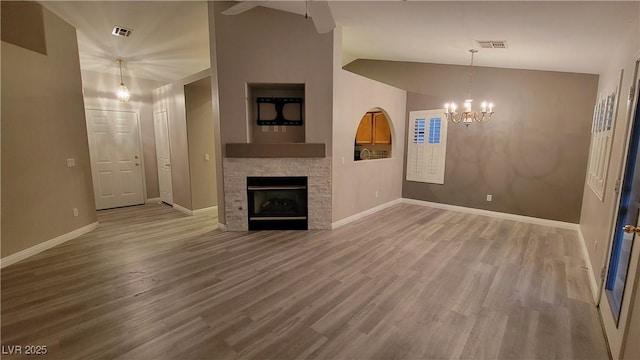 unfurnished living room with vaulted ceiling, wood finished floors, a fireplace, and visible vents