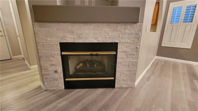 room details with a stone fireplace, wood finished floors, and baseboards