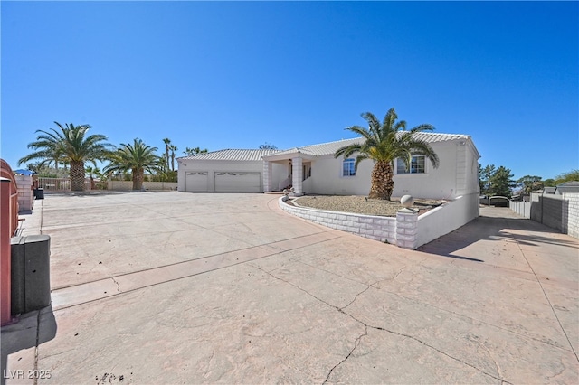 view of front of home featuring fence, a tiled roof, concrete driveway, stucco siding, and a garage