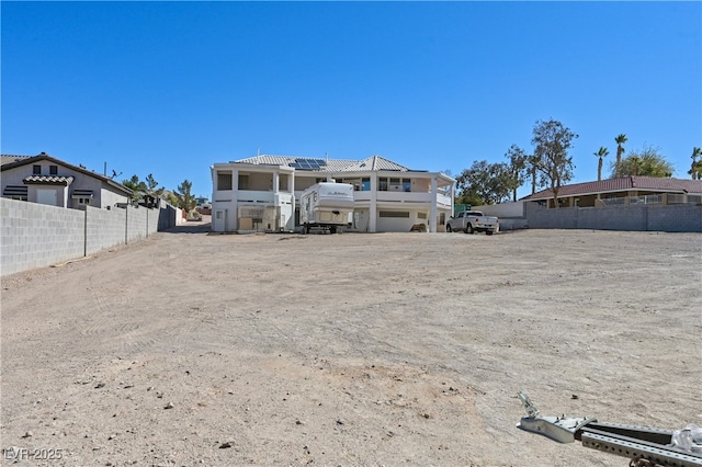 rear view of house featuring fence and solar panels