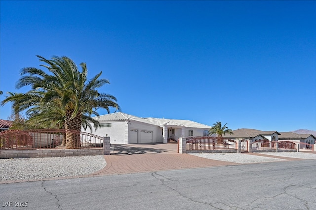 view of front of property featuring a garage, a fenced front yard, a gate, decorative driveway, and stucco siding