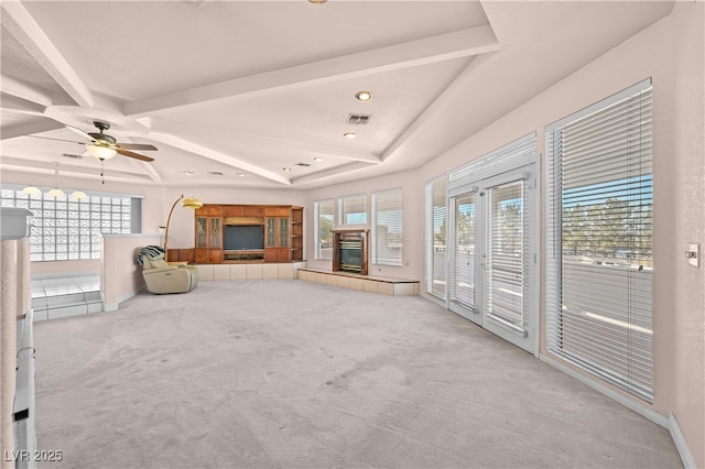 unfurnished living room featuring light carpet, a tiled fireplace, visible vents, and plenty of natural light