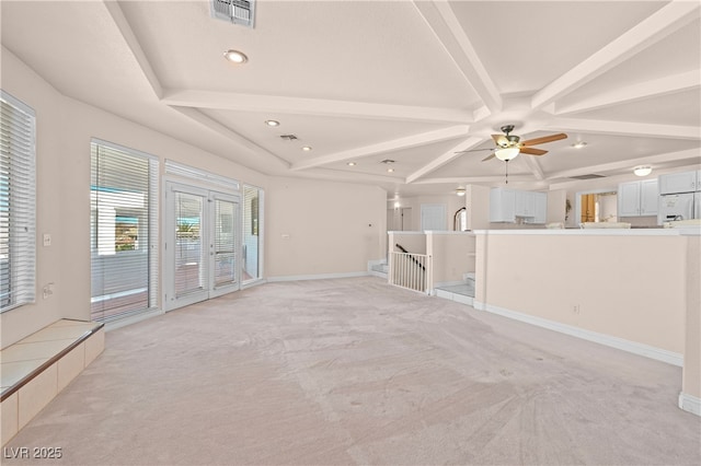 unfurnished living room with beam ceiling, visible vents, light carpet, and baseboards