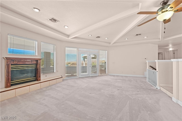 unfurnished living room featuring vaulted ceiling with beams, visible vents, carpet flooring, and a tile fireplace