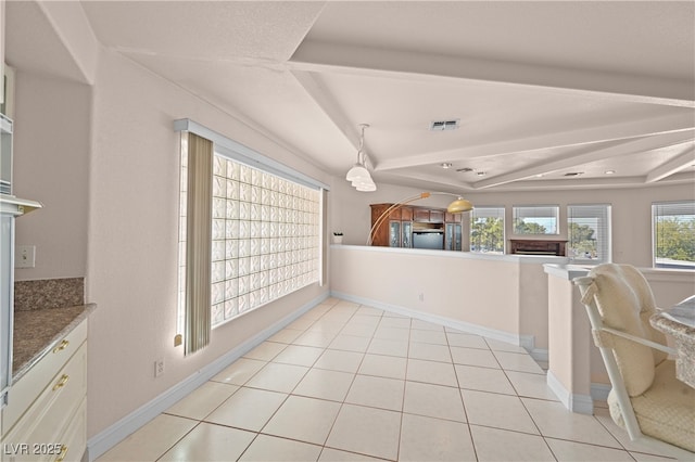 kitchen with light tile patterned floors, visible vents, refrigerator, a tray ceiling, and a fireplace