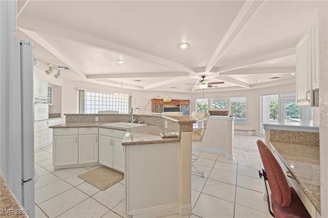 kitchen featuring a kitchen breakfast bar, freestanding refrigerator, a large island with sink, a sink, and light tile patterned flooring