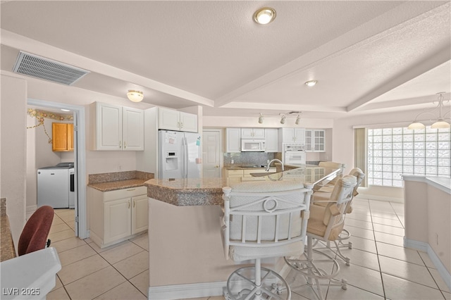 kitchen featuring white appliances, visible vents, independent washer and dryer, tasteful backsplash, and beamed ceiling