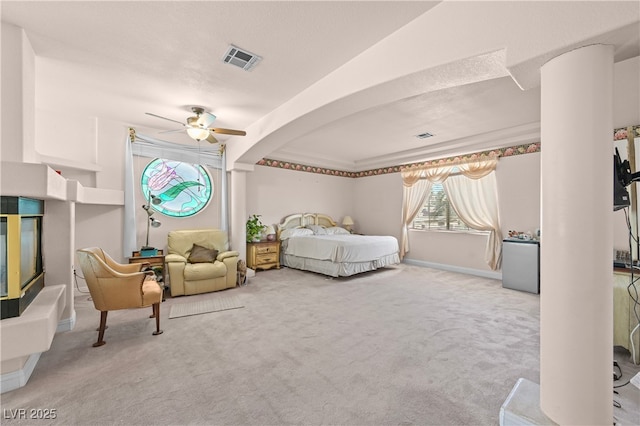 carpeted bedroom featuring a ceiling fan, arched walkways, visible vents, and baseboards