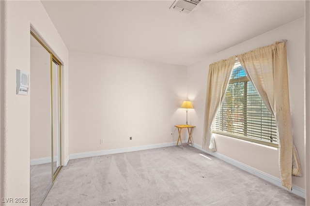 carpeted spare room with visible vents and baseboards