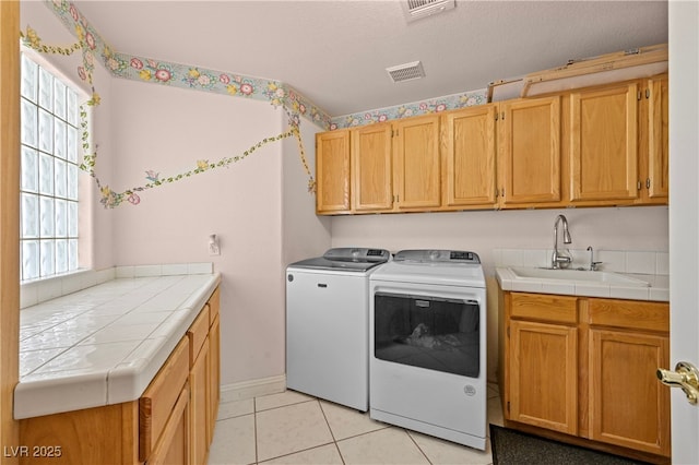 clothes washing area with cabinet space, plenty of natural light, visible vents, independent washer and dryer, and a sink