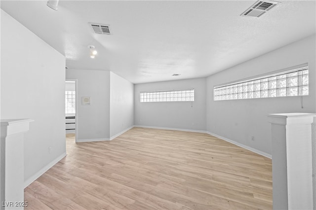 unfurnished room featuring light wood finished floors, baseboards, visible vents, and a textured ceiling