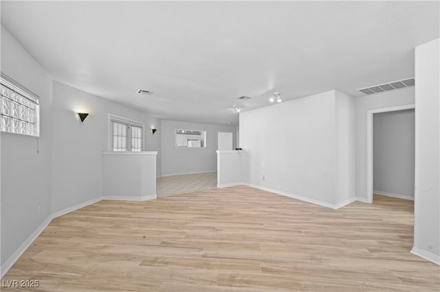 spare room featuring light wood-type flooring, visible vents, and baseboards