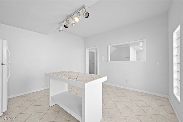 interior space featuring light tile patterned floors, plenty of natural light, and baseboards