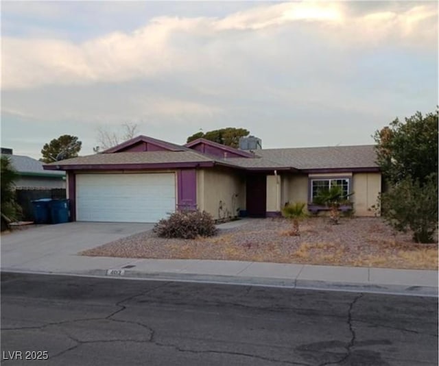 ranch-style home with stucco siding, an attached garage, and driveway