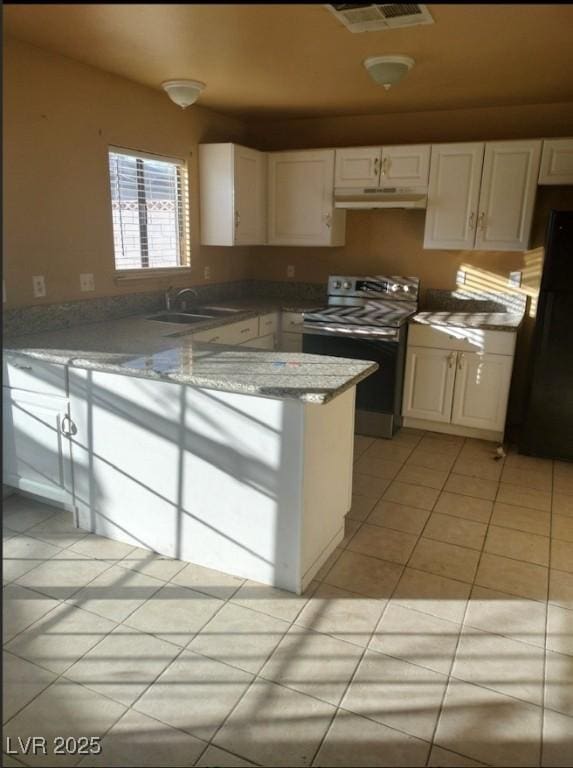 kitchen with under cabinet range hood, stainless steel range with electric stovetop, freestanding refrigerator, white cabinetry, and a sink