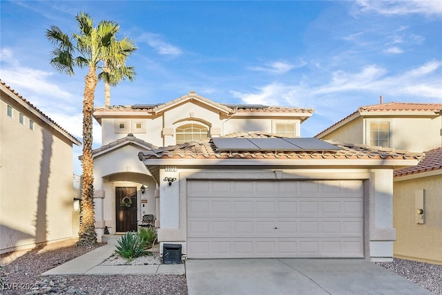 mediterranean / spanish home featuring a tile roof, solar panels, stucco siding, concrete driveway, and a garage