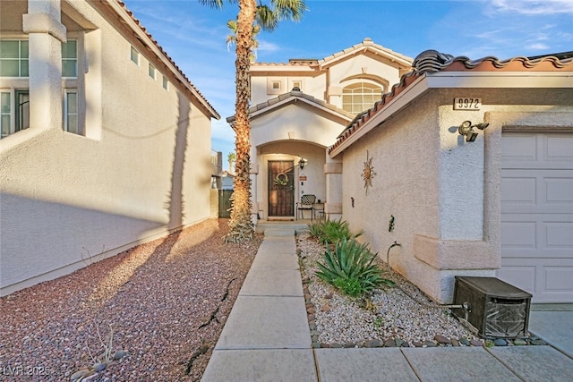 doorway to property featuring an attached garage and stucco siding