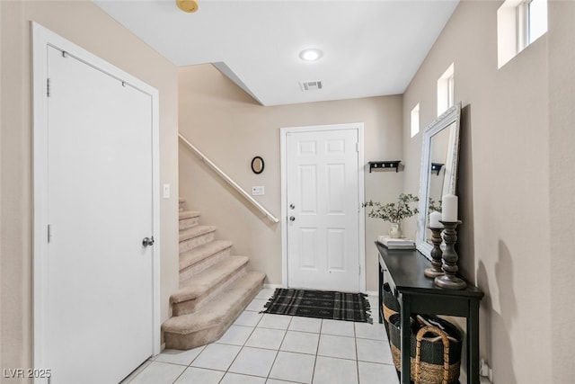 foyer featuring light tile patterned floors, stairway, and visible vents