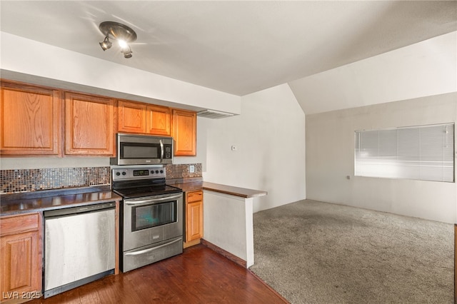 kitchen with stainless steel appliances, dark carpet, dark wood-type flooring, open floor plan, and vaulted ceiling