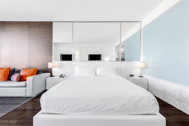 bedroom featuring wood finished floors and wainscoting