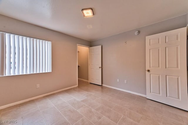 empty room with baseboards and light tile patterned floors