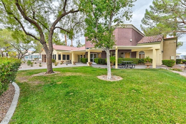 rear view of house with a yard, a tiled roof, and stucco siding