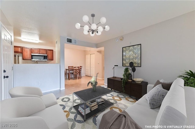 living area featuring baseboards, visible vents, and a notable chandelier