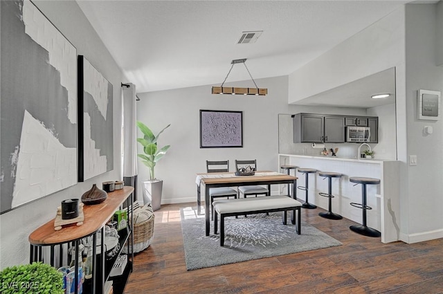 dining space with lofted ceiling, baseboards, visible vents, and dark wood-type flooring