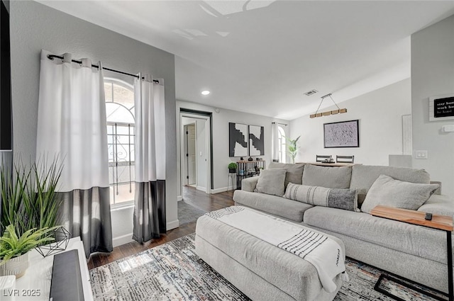 living area with a healthy amount of sunlight, baseboards, wood finished floors, and lofted ceiling