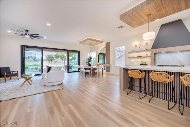 interior space featuring visible vents, arched walkways, baseboards, light wood-style flooring, and recessed lighting