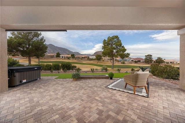 view of patio with a mountain view and a hot tub