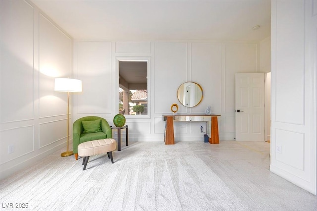 sitting room featuring carpet floors and a decorative wall