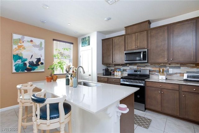3732 Via Gennaro, Henderson, NV 89044 - kitchen featuring stainless steel appliances, light countertops, light tile patterned flooring, backsplash, and a center island with sink